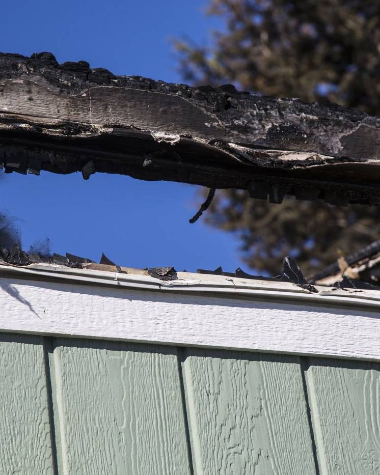 Burned window and charred siding on a fire-damaged home