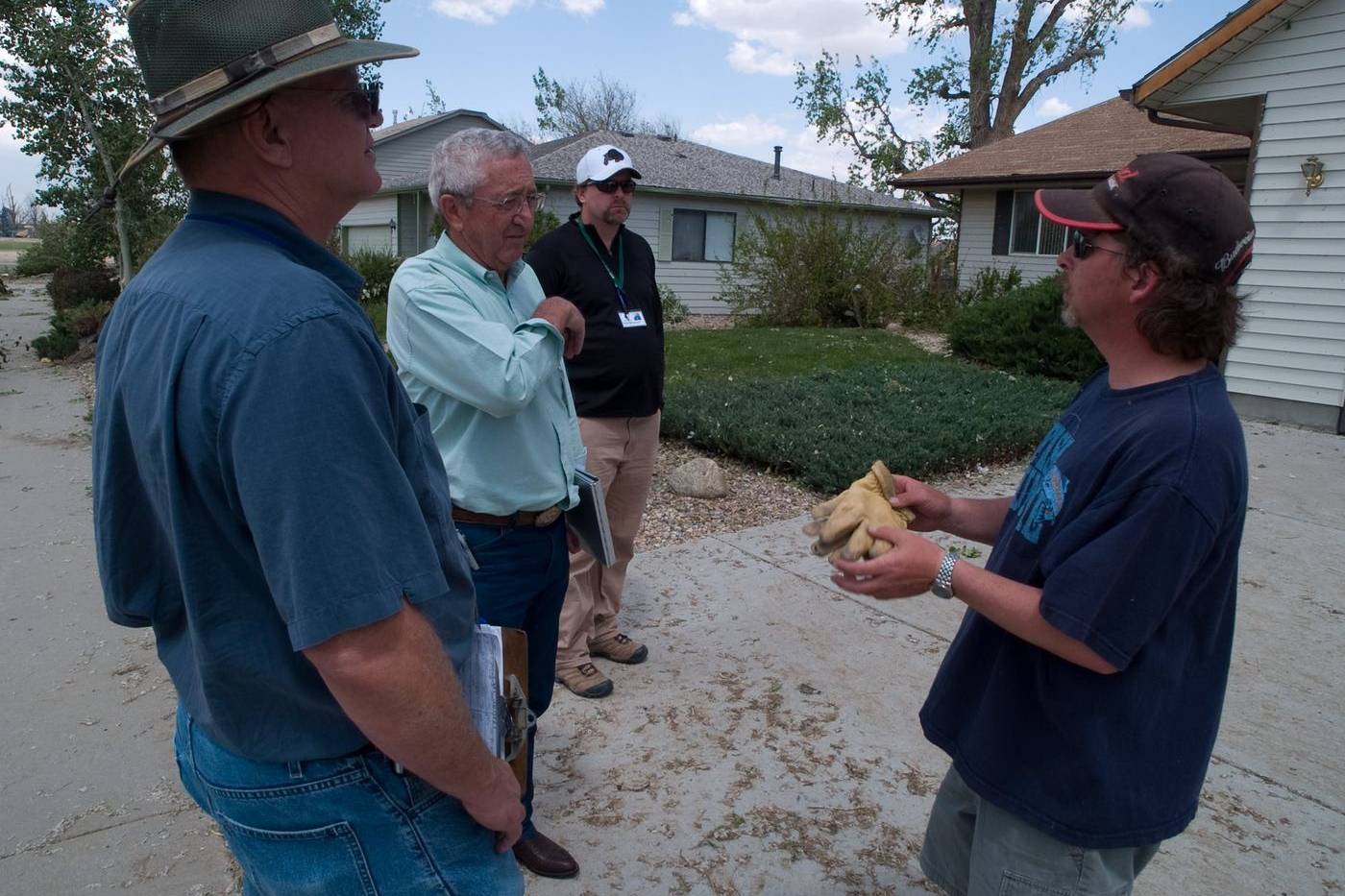Homeowner showing storm damage to assessors outside his house