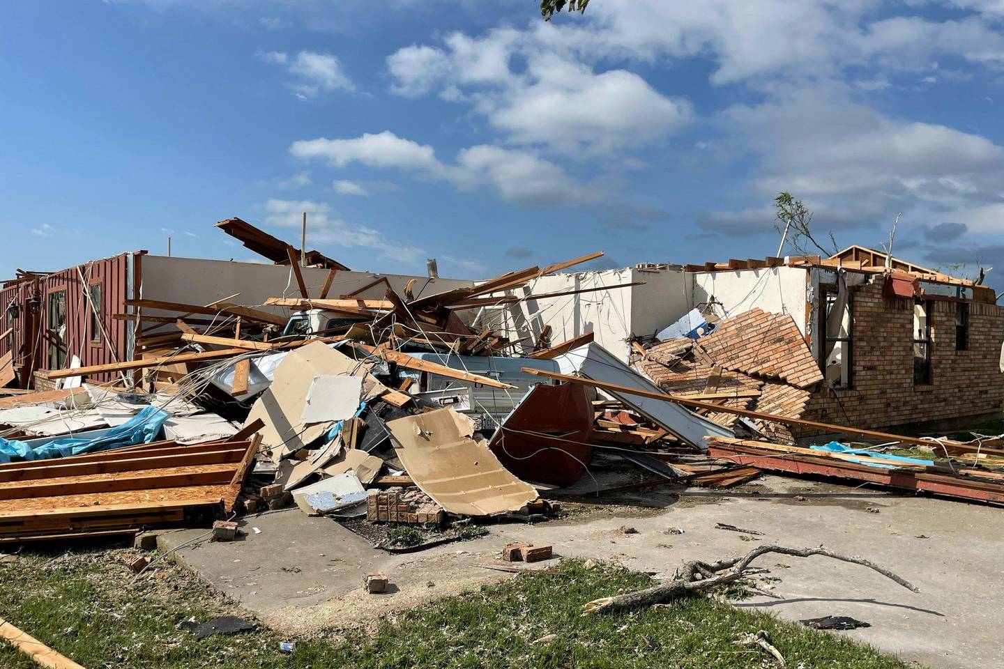 House torn apart by a tornado, with debris across the yard